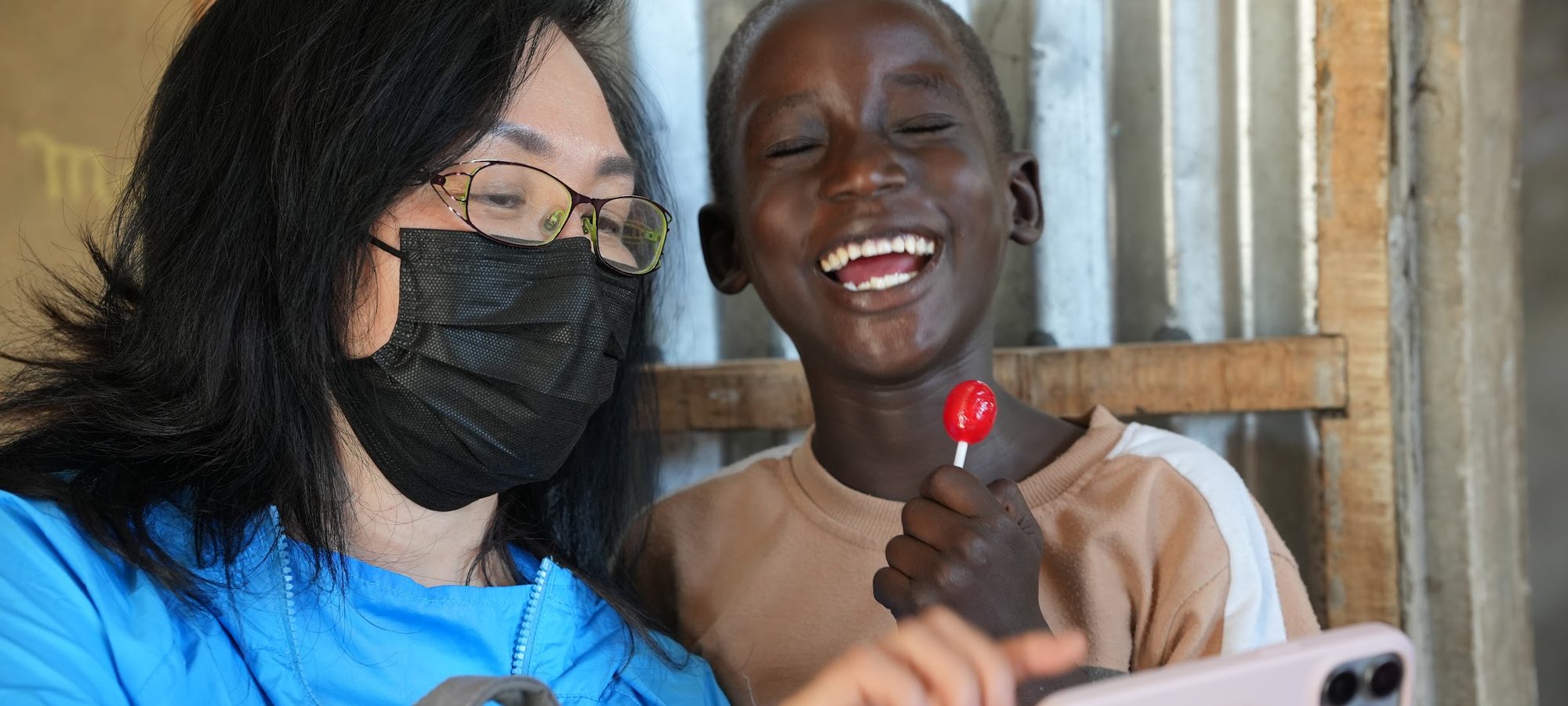 An ACO volunteer laughing with a boy holding a lollipop at a children's programme in Senegal