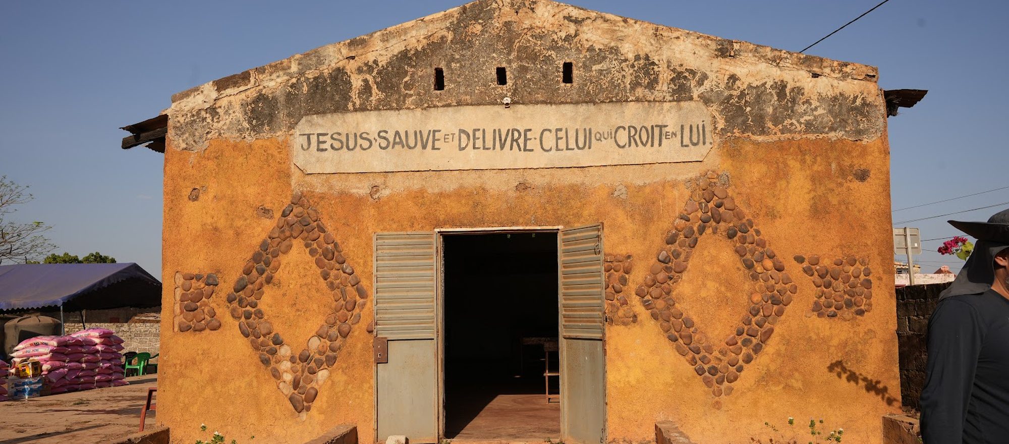 A village church in Senegal, its wall painted with the words Jesus sauve et delivre celui qui croit en lui