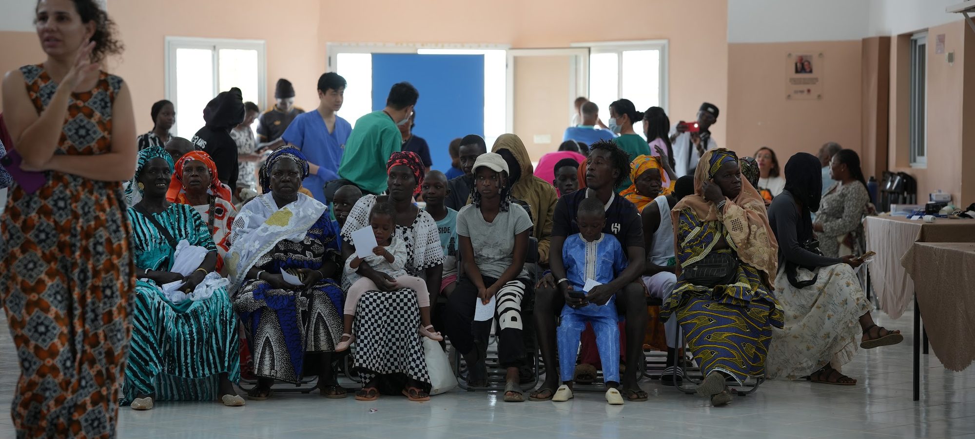 A hall full of families seated and waiting to be seen at the start of an ACO clinic day in Senegal