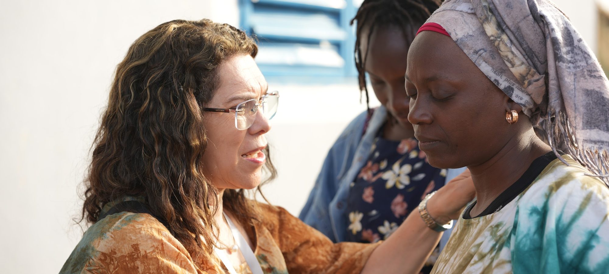 An ACO volunteer speaking gently with a Senegalese woman, a hand resting on her shoulder