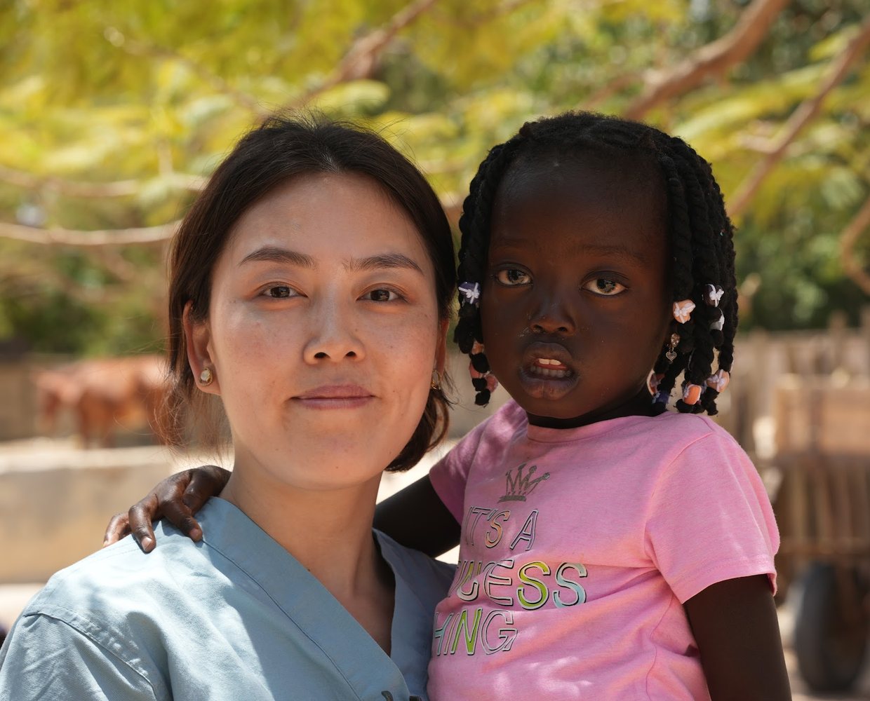 An ACO volunteer holding a young Senegalese girl in her arms at a village outreach