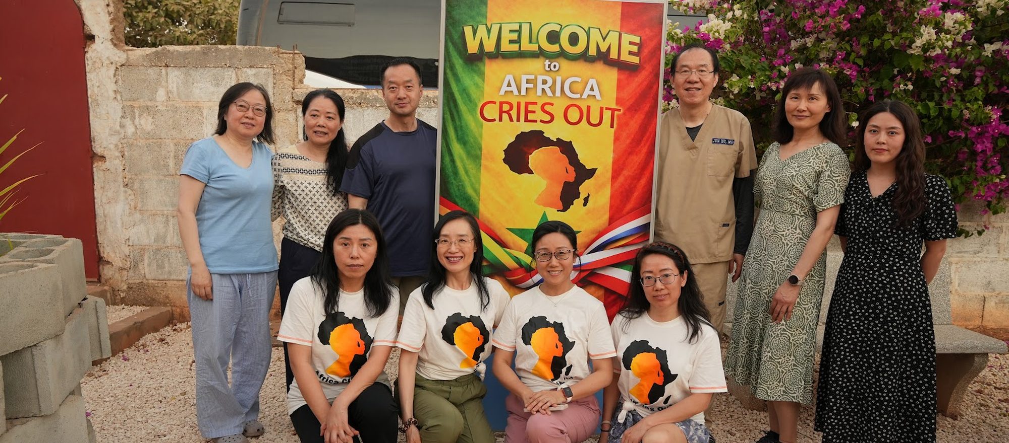 The Africa Cries Out team gathered with local partners beneath an ACO welcome banner in Senegal